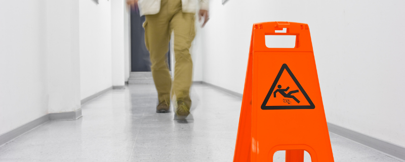 person walking on floor with slippery sign