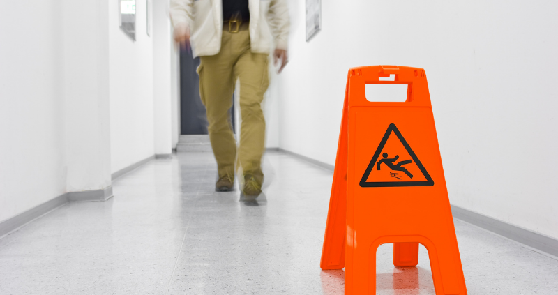 person walking on floor with slippery sign